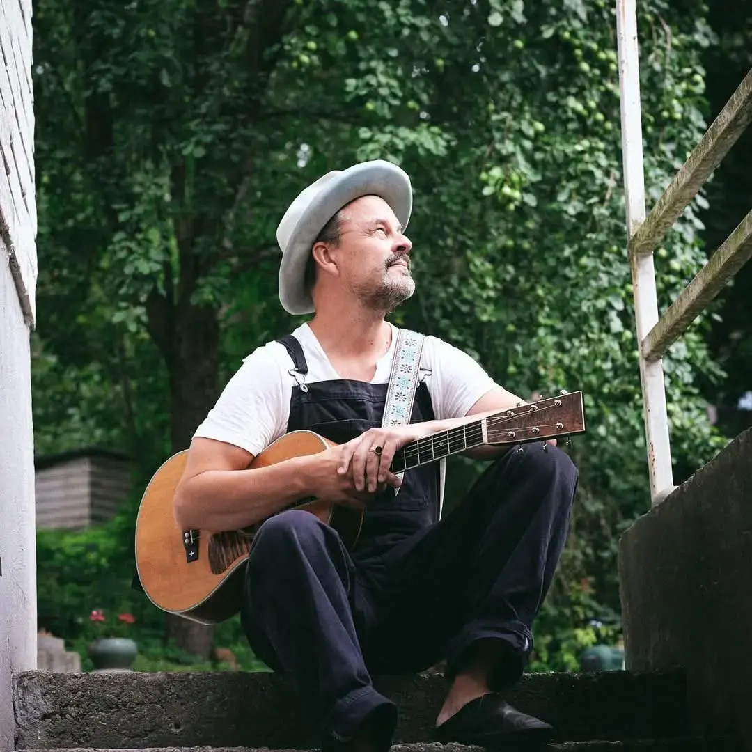 Tuure Kilpeläinen istumassa kitaran kanssa